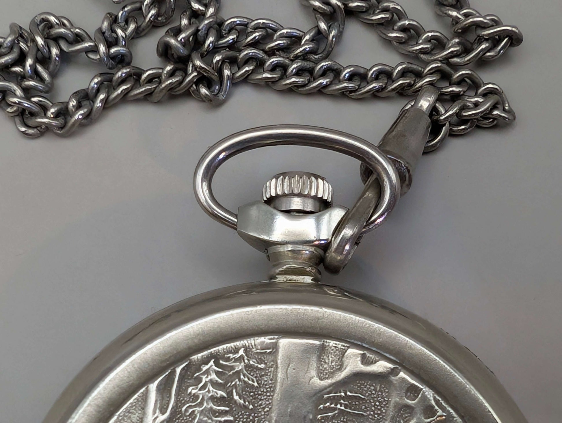 Close-up of Molnija pocket watch with "Wolves in the Forest" engraving, nickel-plated brass, Soviet Union, 1980s.